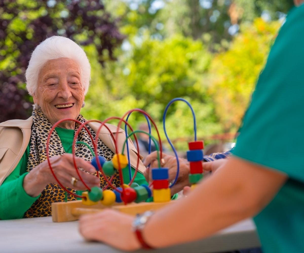 Hand of an elderly woman in the garden of a nursing home or retirement home playing with games to improve the mobility of the hands smiling